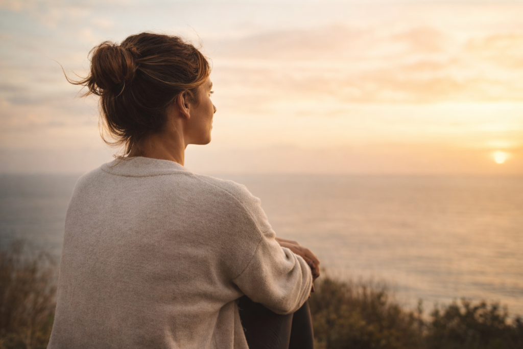 Mujer mirando el horizonte al atardecer sintiendo paz tras alejarse de alguien